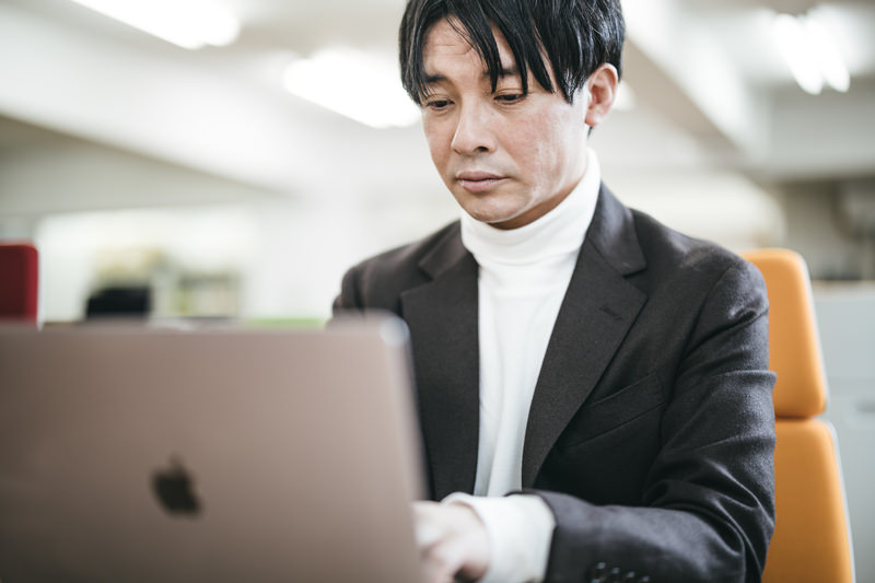 ノートパソコンに向き合って疲れた顔をした男性